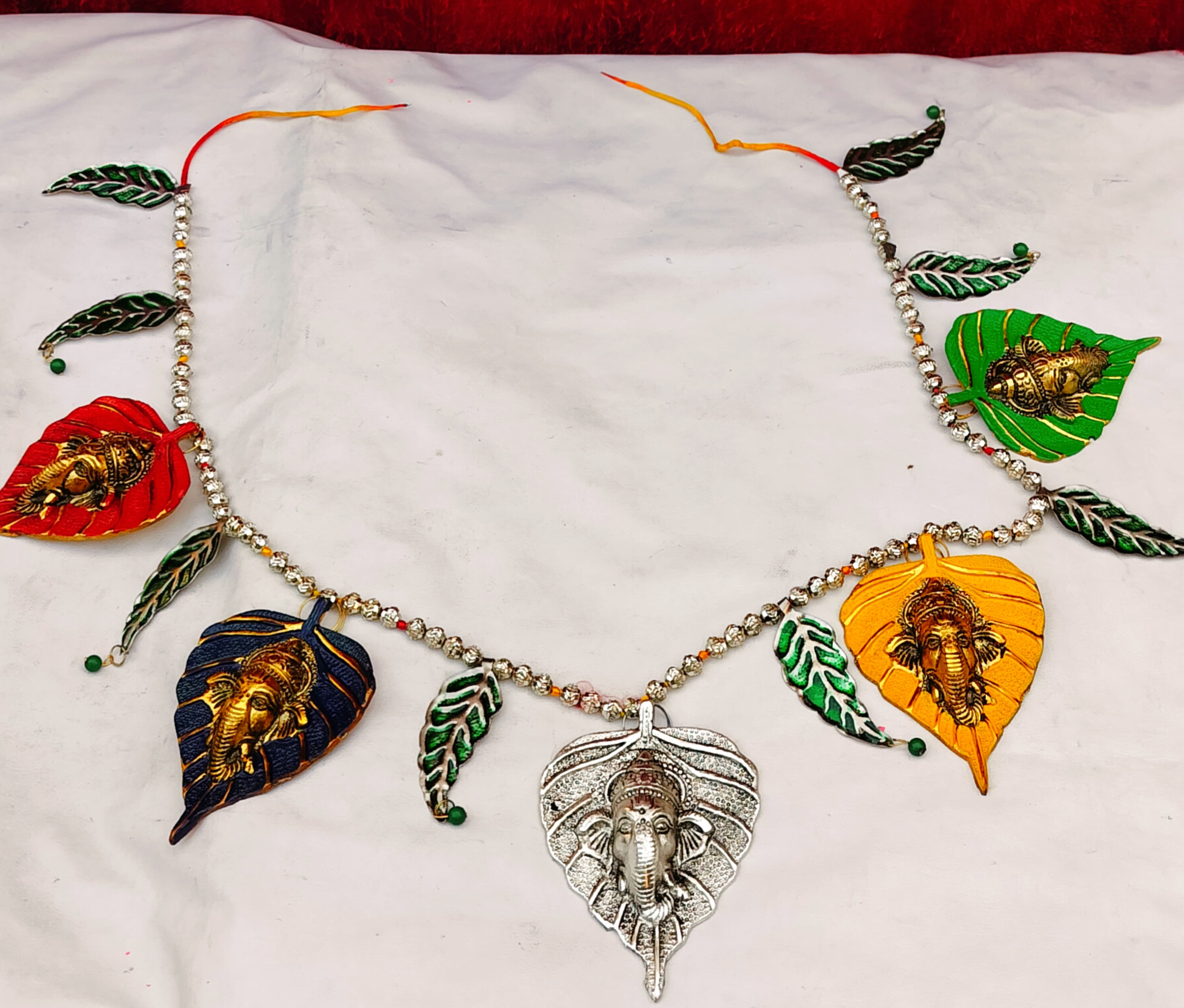 German Silver & gold plated 5 betel leaf Ganesh embossed bandhanwar / toran Description 1. German silver & gold plated betel leaf Ganesh with mango leaf toran / bandhanwar 2. Size - 42" inch (end to end )